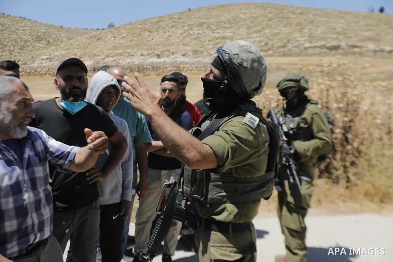 Palestinians and members of the Palestinian Civil Defense gather near the site of a fire on agricultural land around the village of Idhna, west of the West Bank city of Hebron, on June 2, 2026. Palestinian residents said...
