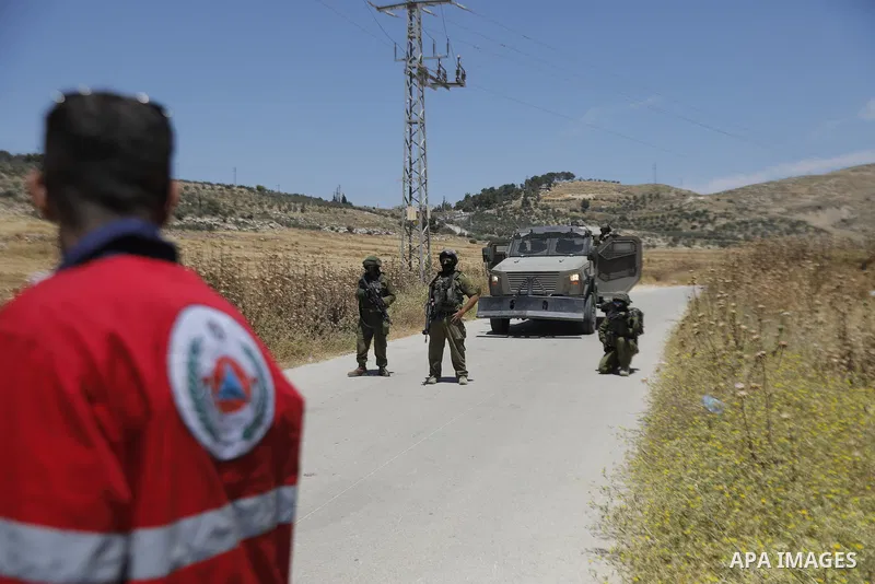Palestinians and members of the Palestinian Civil Defense gather near the site of a fire on agricultural land around the village of Idhna, west of the West Bank city of Hebron, on June 2, 2026. Palestinian residents said...