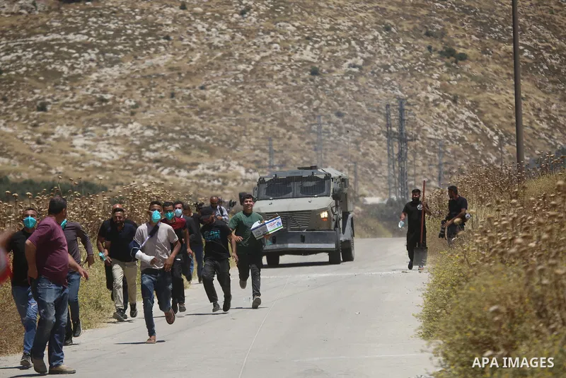 Palestinians and members of the Palestinian Civil Defense gather near the site of a fire on agricultural land around the village of Idhna, west of the West Bank city of Hebron, on June 2, 2026. Palestinian residents said...