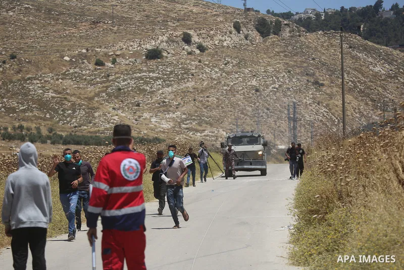 Palestinians and members of the Palestinian Civil Defense gather near the site of a fire on agricultural land around the village of Idhna, west of the West Bank city of Hebron, on June 2, 2026. Palestinian residents said...