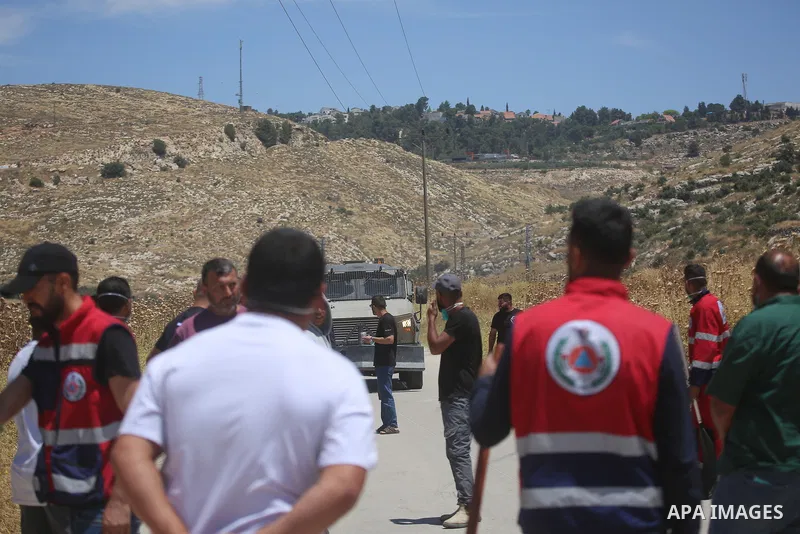 Palestinians and members of the Palestinian Civil Defense gather near the site of a fire on agricultural land around the village of Idhna, west of the West Bank city of Hebron, on June 2, 2026. Palestinian residents said...