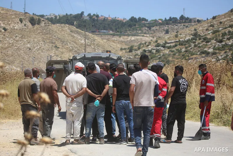 Palestinians and members of the Palestinian Civil Defense gather near the site of a fire on agricultural land around the village of Idhna, west of the West Bank city of Hebron, on June 2, 2026. Palestinian residents said...