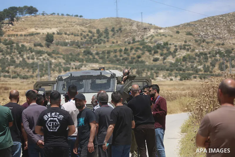 Palestinians and members of the Palestinian Civil Defense gather near the site of a fire on agricultural land around the village of Idhna, west of the West Bank city of Hebron, on June 2, 2026. Palestinian residents said...