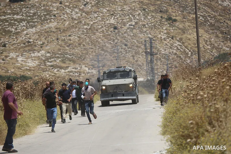 Palestinians and members of the Palestinian Civil Defense gather near the site of a fire on agricultural land around the village of Idhna, west of the West Bank city of Hebron, on June 2, 2026. Palestinian residents said...