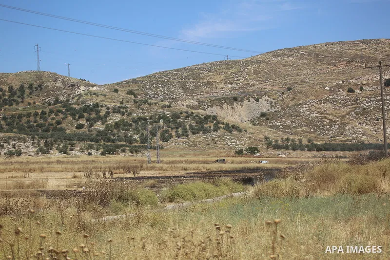 Palestinians and members of the Palestinian Civil Defense gather near the site of a fire on agricultural land around the village of Idhna, west of the West Bank city of Hebron, on June 2, 2026. Palestinian residents said...