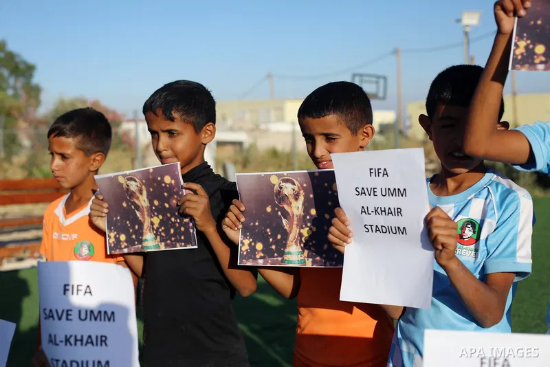 Children hold placards at a playground threatened with demolition in the village of Umm al-Khair, south of Hebron in the West Bank, on June 11, 2026. The children sent a message to FIFA at the start of the World Cup, cal...