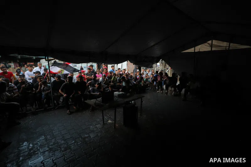 Palestinians watch a football match between the Egypt and Argentina national teams inside a tent at a United Nations Relief and Works Agency (UNRWA) school shelter in the Nuseirat refugee camp, in the central Gaza Strip,...