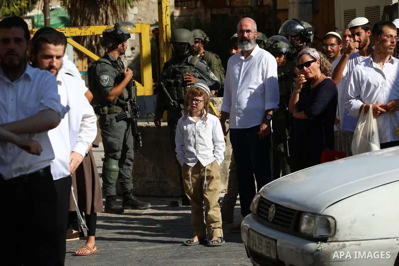 Israeli settlers walk through the Old City of Hebron in the southern West Bank under heavy protection from Israeli security forces on July 18, 2026. Israeli security forces were deployed throughout the area to secure the...