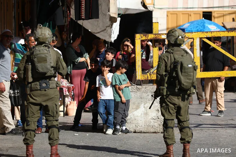 Israeli settlers walk through the Old City of Hebron in the southern West Bank under heavy protection from Israeli security forces on July 18, 2026. Israeli security forces were deployed throughout the area to secure the...
