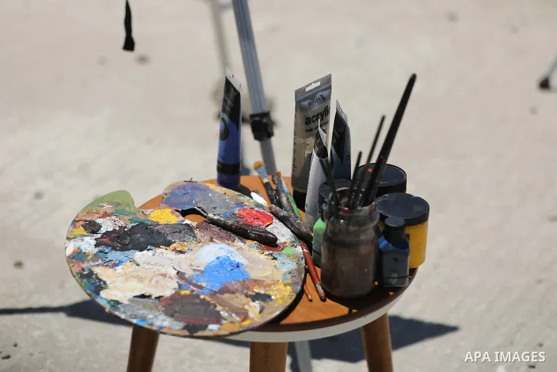 Palestinian visual artist Jana Mahmoud Abu Harbid, 21, paints on the roof of her family's damaged home after returning to northern Gaza and finding her studio destroyed following the war, in Gaza City, on July 20, 2026....
