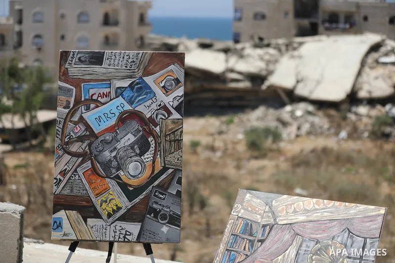 Palestinian visual artist Jana Mahmoud Abu Harbid, 21, paints on the roof of her family's damaged home after returning to northern Gaza and finding her studio destroyed following the war, in Gaza City, on July 20, 2026....