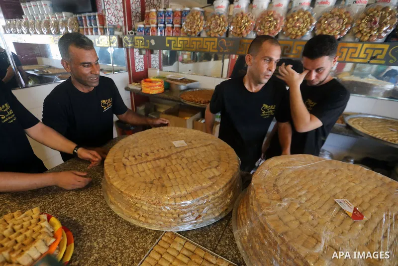 Workers prepare assorted sweets at a confectionery shop in Gaza City on July 23, 2026, a day before the announcement of the Palestinian General Secondary Education Examination (Tawjihi) results, as families prepare to ce...