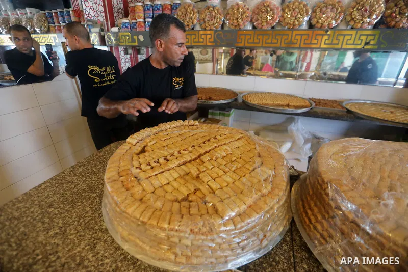 Workers prepare assorted sweets at a confectionery shop in Gaza City on July 23, 2026, a day before the announcement of the Palestinian General Secondary Education Examination (Tawjihi) results, as families prepare to ce...