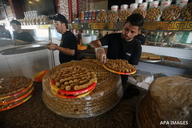 Workers prepare assorted sweets at a confectionery shop in Gaza City on July 23, 2026, a day before the announcement of the Palestinian General Secondary Education Examination (Tawjihi) results, as families prepare to ce...