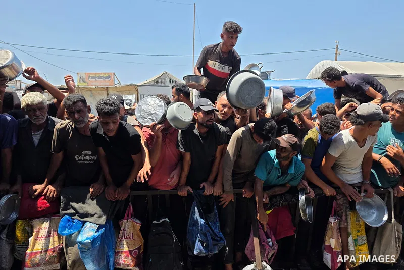 Displaced Palestinians gather to receive meals from a charity kitchen in the al-Mawasi area, west of Khan Younis, southern Gaza Strip, on August 1, 2026. The gathering comes amid ongoing food shortages and deteriorating...