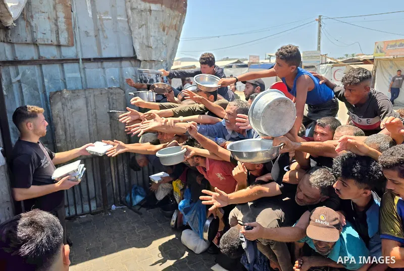 Displaced Palestinians gather to receive meals from a charity kitchen in the al-Mawasi area, west of Khan Younis, southern Gaza Strip, on August 1, 2026. The gathering comes amid ongoing food shortages and deteriorating...