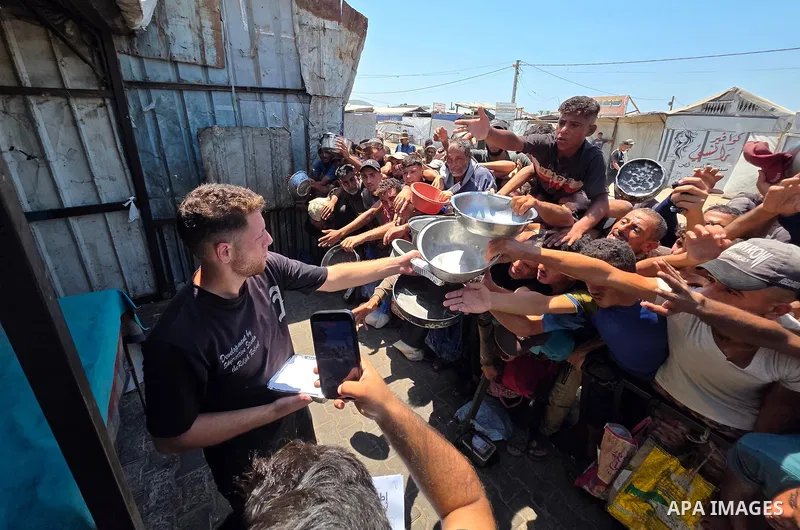 Displaced Palestinians gather to receive meals from a charity kitchen in the al-Mawasi area, west of Khan Younis, southern Gaza Strip, on August 1, 2026. The gathering comes amid ongoing food shortages and deteriorating...