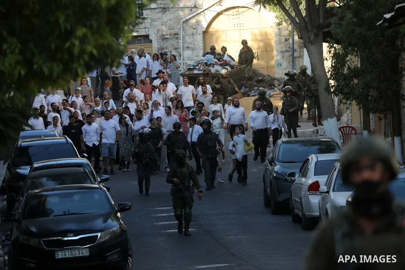Israeli settlers walk through the Old City of Hebron, in the occupied West Bank, under the protection of Israeli troops after the forces closed roads and alleys in the area, restricting the movement of Palestinian reside...