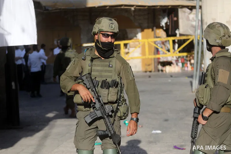 Israeli settlers walk through the Old City of Hebron, in the occupied West Bank, under the protection of Israeli troops after the forces closed roads and alleys in the area, restricting the movement of Palestinian reside...