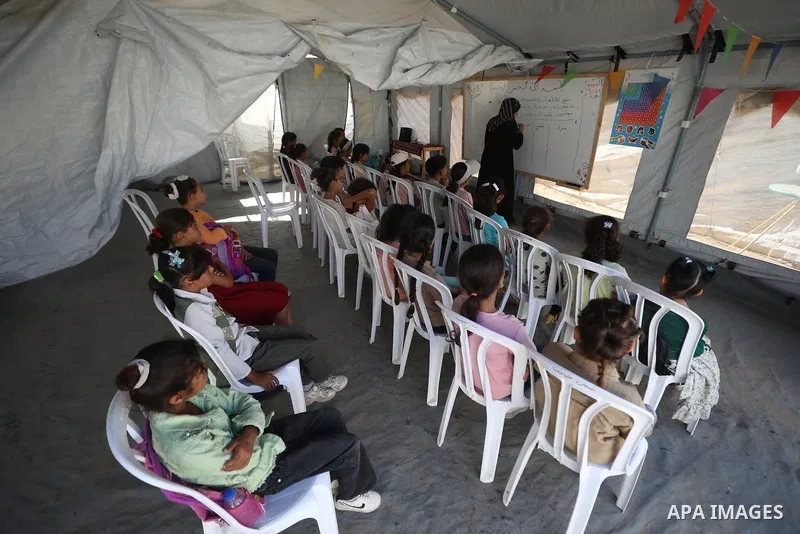 Palestinian students attend a lesson inside a tent in al-Bureij camp in the central Gaza Strip on September 26, 2026, as the new academic year resumes. Classes are being held amid widespread damage to schools and shortag...