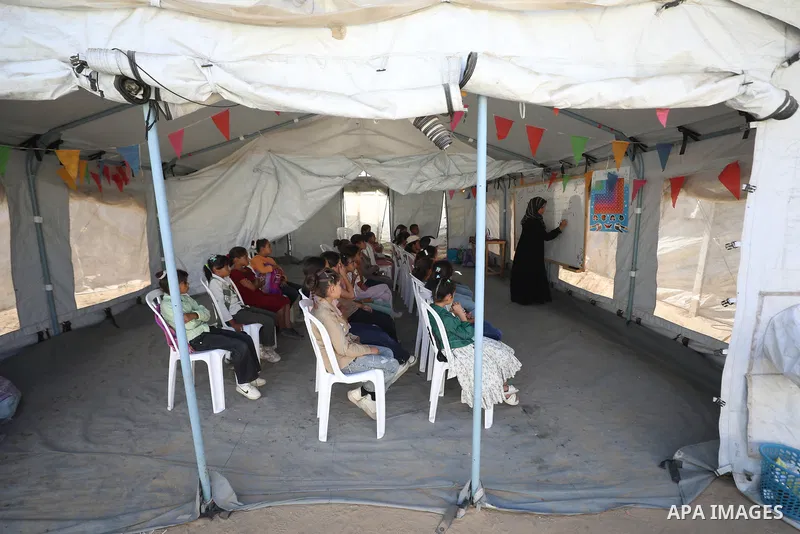 Palestinian students attend a lesson inside a tent in al-Bureij camp in the central Gaza Strip on September 26, 2026, as the new academic year resumes. Classes are being held amid widespread damage to schools and shortag...