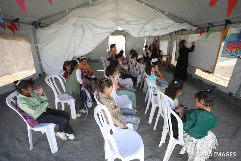 Palestinian students attend a lesson inside a tent in al-Bureij camp in the central Gaza Strip on September 26, 2026, as the new academic year resumes. Classes are being held amid widespread damage to schools and shortag...