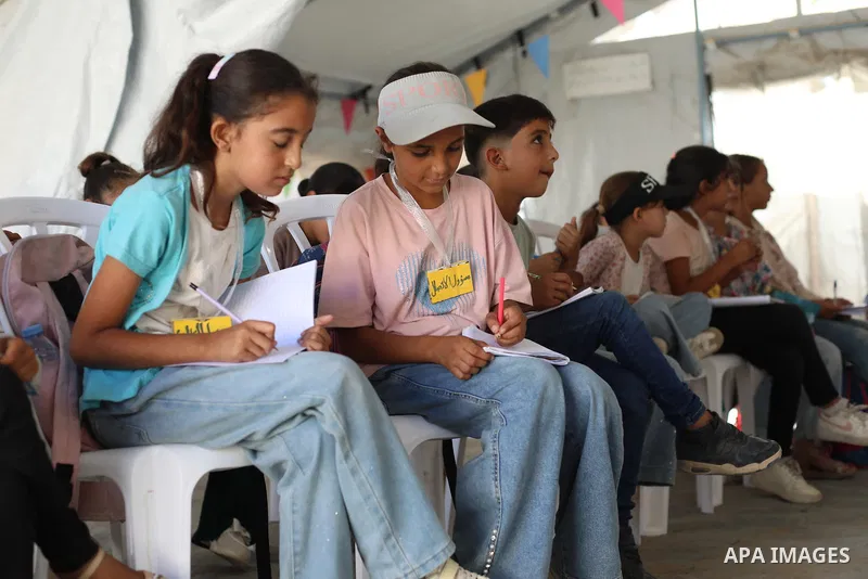 Palestinian students attend a lesson inside a tent in al-Bureij camp in the central Gaza Strip on September 26, 2026, as the new academic year resumes. Classes are being held amid widespread damage to schools and shortag...