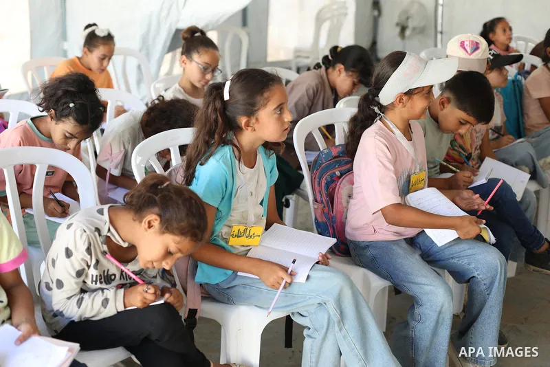 Palestinian students attend a lesson inside a tent in al-Bureij camp in the central Gaza Strip on September 26, 2026, as the new academic year resumes. Classes are being held amid widespread damage to schools and shortag...