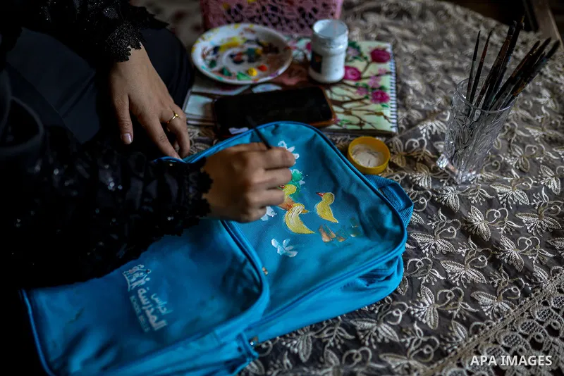 Palestinian visual artist Hala Abu Hamda, 18, paints and colors children’s bags inside her home in the al-Nasr neighborhood of Gaza City on September 27, 2026, as the new academic year begins. Students in the Gaza Strip...
