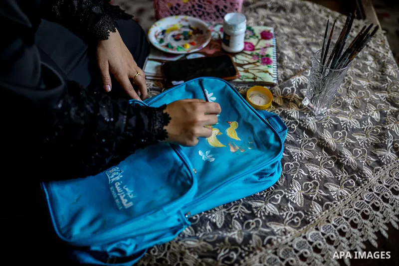 Palestinian visual artist Hala Abu Hamda, 18, paints and colors children’s bags inside her home in the al-Nasr neighborhood of Gaza City on September 27, 2026, as the new academic year begins. Students in the Gaza Strip...