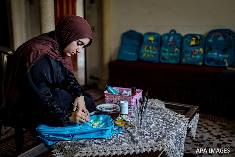 Palestinian visual artist Hala Abu Hamda, 18, paints and colors children’s bags inside her home in the al-Nasr neighborhood of Gaza City on September 27, 2026, as the new academic year begins. Students in the Gaza Strip...