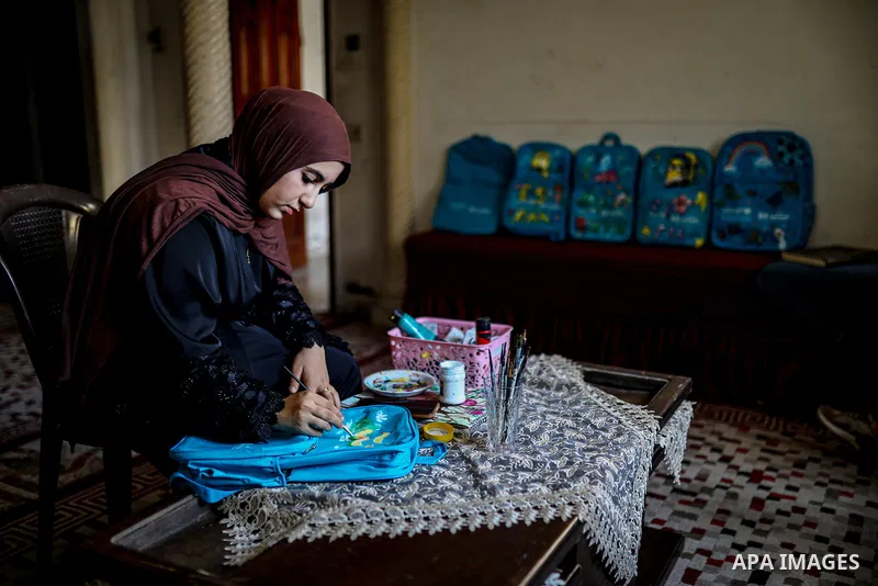 Palestinian visual artist Hala Abu Hamda, 18, paints and colors children’s bags inside her home in the al-Nasr neighborhood of Gaza City on September 27, 2026, as the new academic year begins. Students in the Gaza Strip...