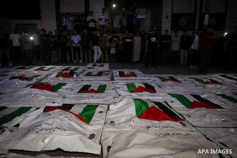 Palestinians light candles and mourn beside the bodies of loved ones recovered from beneath the rubble of destroyed homes outside Al-Awda Hospital in the Nuseirat refugee camp, central Gaza Strip, on September 28, 2026....