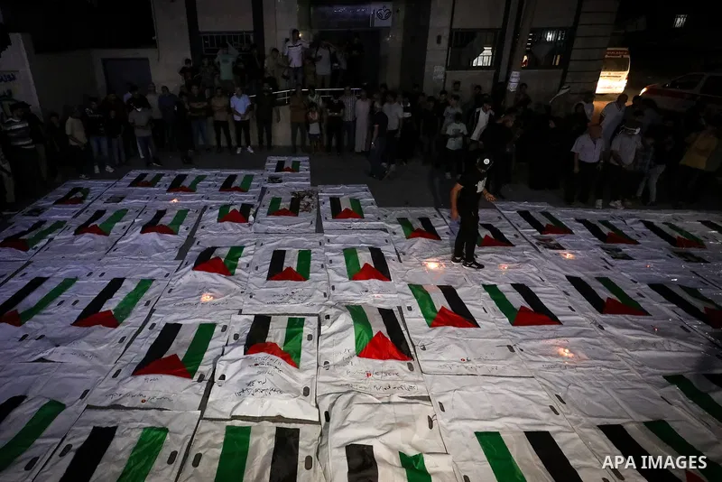 Palestinians light candles and mourn beside the bodies of loved ones recovered from beneath the rubble of destroyed homes outside Al-Awda Hospital in the Nuseirat refugee camp, central Gaza Strip, on September 28, 2026....