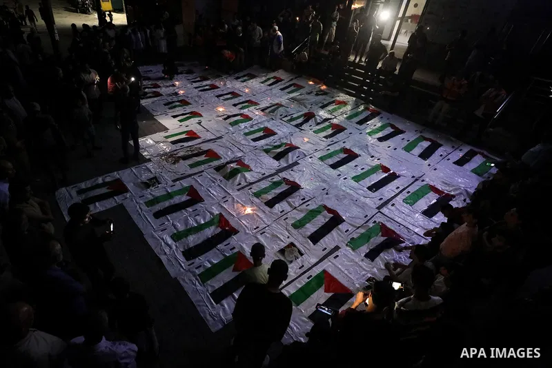 Palestinians light candles and mourn beside the bodies of loved ones recovered from beneath the rubble of destroyed homes outside Al-Awda Hospital in the Nuseirat refugee camp, central Gaza Strip, on September 28, 2026....