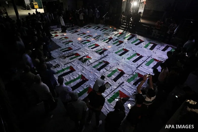 Palestinians light candles and mourn beside the bodies of loved ones recovered from beneath the rubble of destroyed homes outside Al-Awda Hospital in the Nuseirat refugee camp, central Gaza Strip, on September 28, 2026....