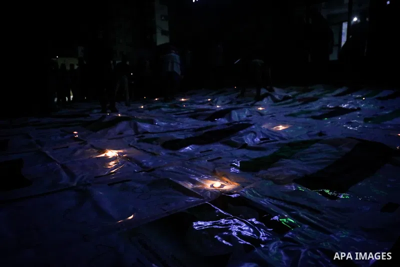 Palestinians light candles and mourn beside the bodies of loved ones recovered from beneath the rubble of destroyed homes outside Al-Awda Hospital in the Nuseirat refugee camp, central Gaza Strip, on September 28, 2026....