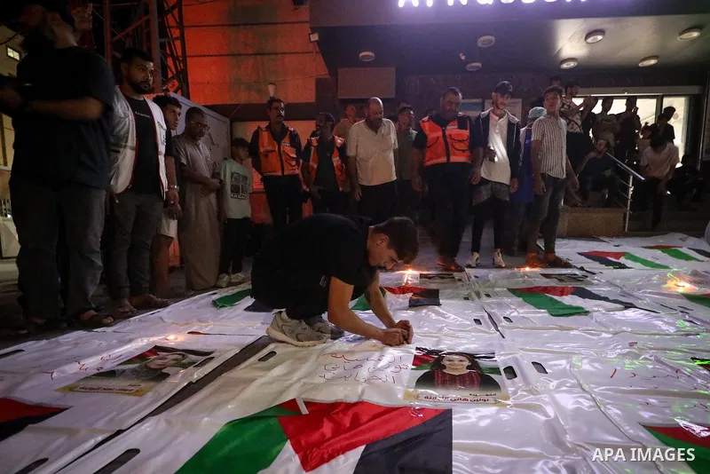 Palestinians light candles and mourn beside the bodies of loved ones recovered from beneath the rubble of destroyed homes outside Al-Awda Hospital in the Nuseirat refugee camp, central Gaza Strip, on September 28, 2026....