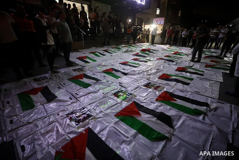 Palestinians light candles and mourn beside the bodies of loved ones recovered from beneath the rubble of destroyed homes outside Al-Awda Hospital in the Nuseirat refugee camp, central Gaza Strip, on September 28, 2026....