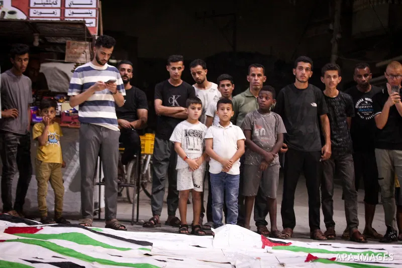 Palestinians light candles and mourn beside the bodies of loved ones recovered from beneath the rubble of destroyed homes outside Al-Awda Hospital in the Nuseirat refugee camp, central Gaza Strip, on September 28, 2026....