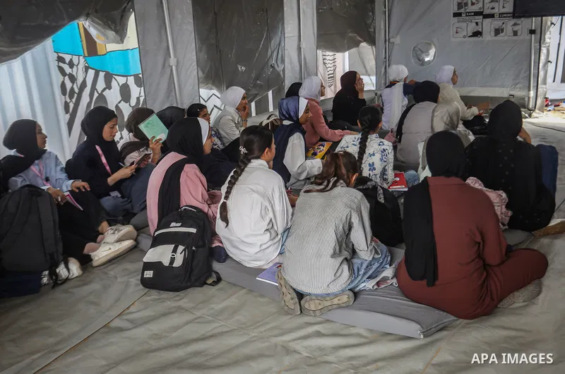 Palestinian students attend classes inside tents at the Saraya education point in the Gaza Strip on October 11, 2026, as education continues under difficult conditions and with shortages of school equipment. Students sit...