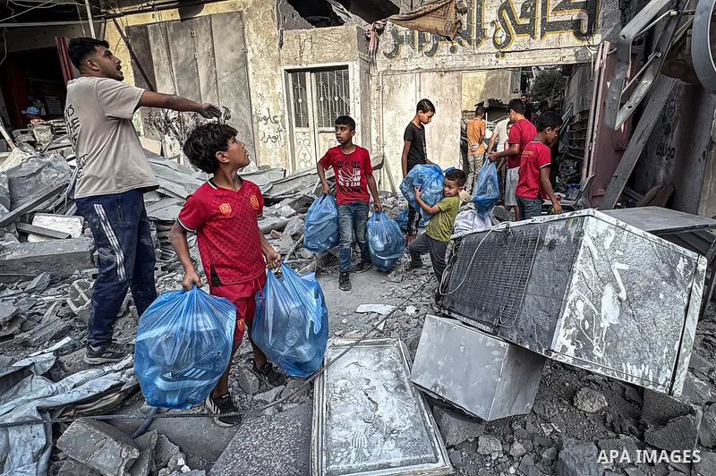 Palestinians inspect their belongings amid the rubble following an overnight Israeli airstrike that targeted a residential building in the al-Maghazi refugee camp in the central Gaza Strip, on October 16, 2026. Photo by...