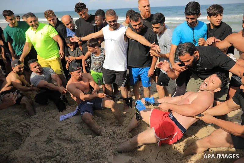 Young Palestinians exercise and take part in sports activities on the beach in Nuseirat, in the central Gaza Strip, on October 16, 2026. With sports facilities damaged by the war and the absence of sports clubs, they use...