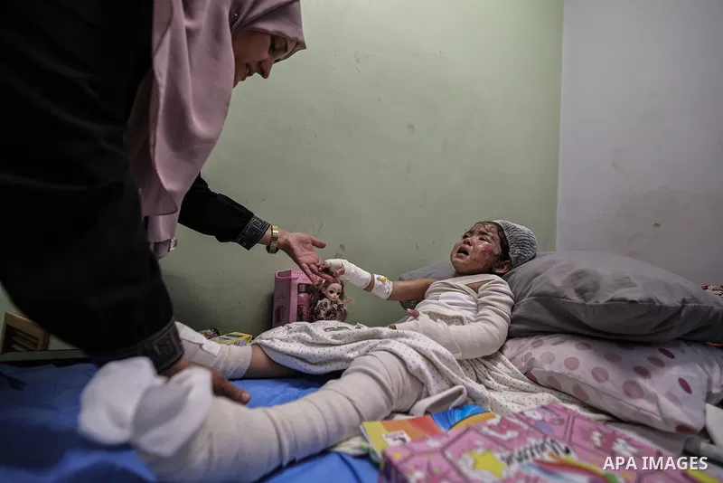 Palestinian child Maryam Ganem, two and a half years old, receives medical treatment for burns at al-Shifa Hospital in Gaza City, on October 15, 2026, as relatives stay by her side. Ganem was orphaned after her family wa...