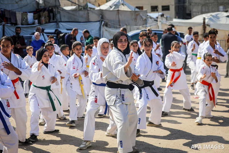 Palestinians take part in a sports event organized by the Palestinian Karate Federation in the southern governorates under the slogan “From beneath the rubble, 1000 new dreams were born,” in Gaza City, on Tuesday, Octobe...