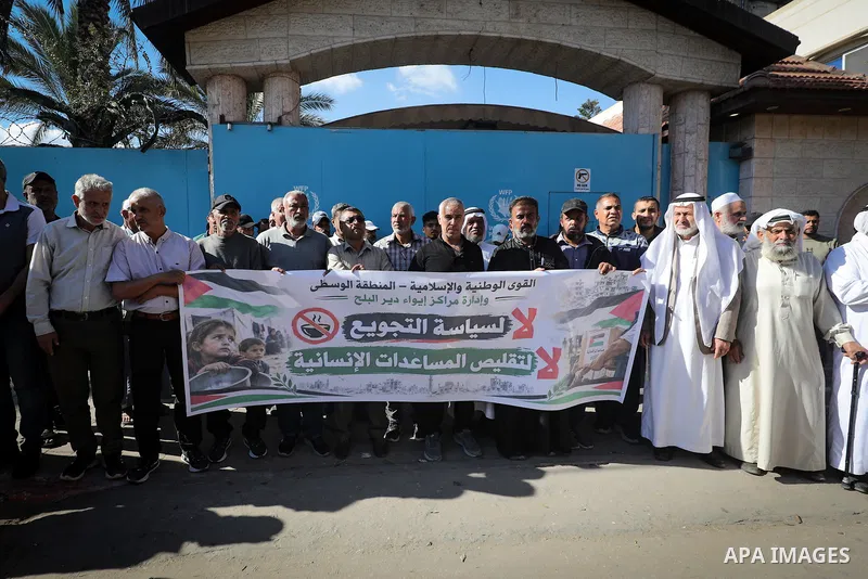 Displaced Palestinians take part in a protest outside the World Food Programme (WFP) office in Deir el-Balah, central Gaza Strip, on October 21, 2026, against cuts to food assistance for displaced families amid worsening...