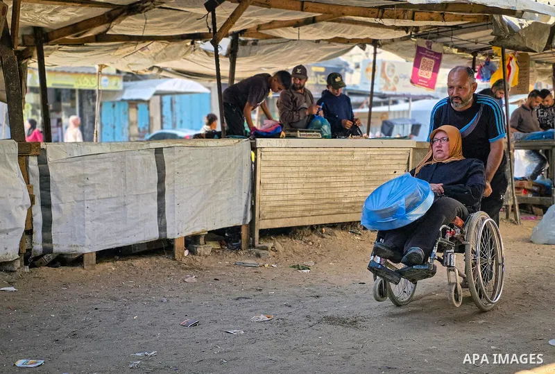 Palestinian vendors and residents stand beside empty fruit and vegetable stalls at a market in Khan Younis, southern Gaza Strip, on October 21, 2026, amid severe shortages of fresh produce and record-high prices for rema...