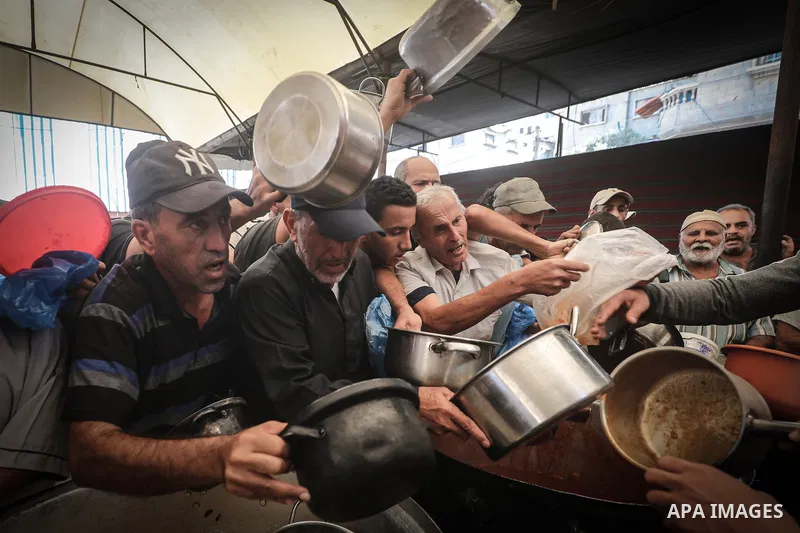 Displaced Palestinians gather to receive free meals at a food distribution point in the Nuseirat refugee camp, central Gaza Strip, on October 22, 2026, amid worsening food insecurity caused by the war. On October 19, the...