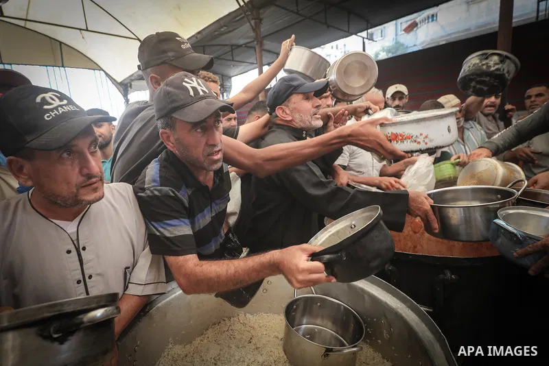 Displaced Palestinians gather to receive free meals at a food distribution point in the Nuseirat refugee camp, central Gaza Strip, on October 22, 2026, amid worsening food insecurity caused by the war. On October 19, the...