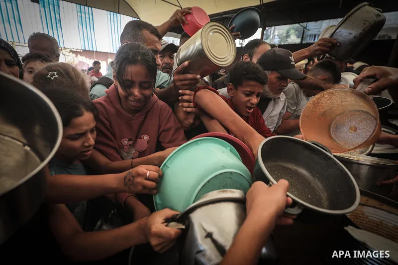 Displaced Palestinians gather to receive free meals at a food distribution point in the Nuseirat refugee camp, central Gaza Strip, on October 22, 2026, amid worsening food insecurity caused by the war. On October 19, the...